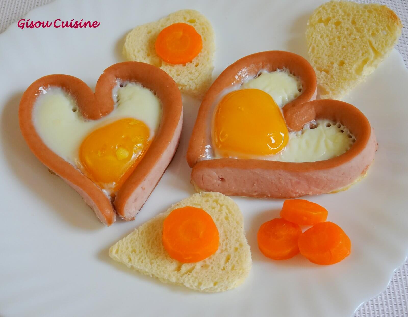 Oeuf au plat dans une saucisse de strasbourg en forme de coeur avec quelques rondelles de carottes. Idée saint Valentin.